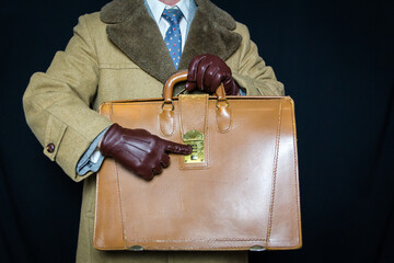 Portrait of Man in Fur Coat and Leather Gloves Pointing to Combination Lock on Briefcase on Black...