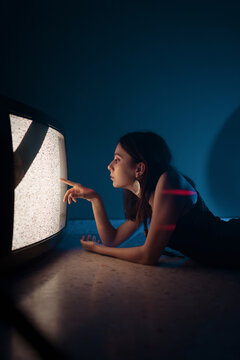Woman lying down near old television in darkness
