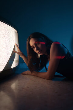Woman lying down near old television in darkness