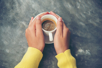 Close up hands of woman sitting office desk holding sweet coffee cup relax and enjoy with happy time. Hot coffee mug in hand. Woman holding coffee cup relaxing after work at office warm taste in cafe