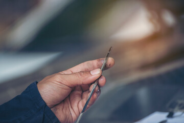 Car Mechanic man hand checking dipstick engine oil car mechanical on site service. Close up hand man check engine oil level Locate dipstick, wipe clean, check dipstick level before fill up engine oil