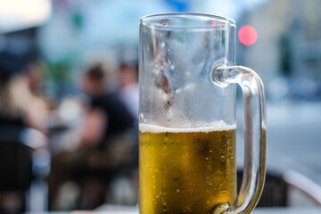 Half empty glass of light beer in a pub. Selective focus
