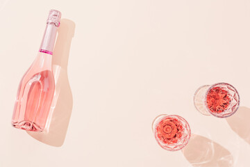 Two fashion glasses with pattern and bottle of rose sparkling wine with dark shadows. Summer drink concept.