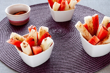 Fruit sticks with chili spice. Fresh raw sweet cut fruit with spicy chile and cocoa condiment...