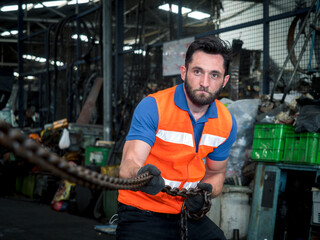 Portrait of mechanical engineer pulling chain against machine environment in the factory.
