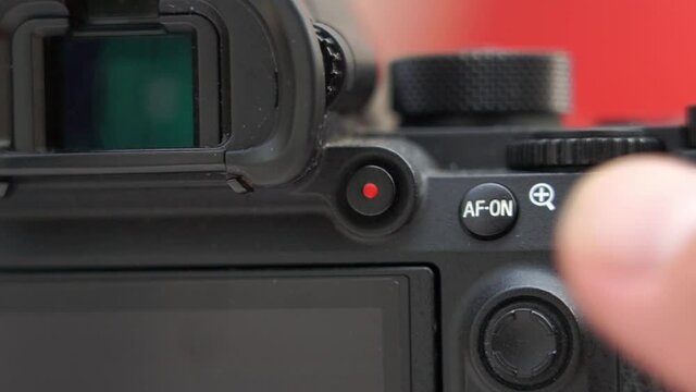 macro close-up of finger A male photographer's hand presses the recording and stops recording. Behind the mirrorless camera to record the shooting process