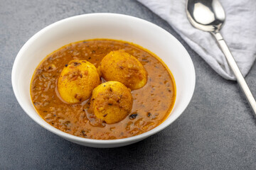 Fried egg curry or anda masala served in a white bowl and copy space