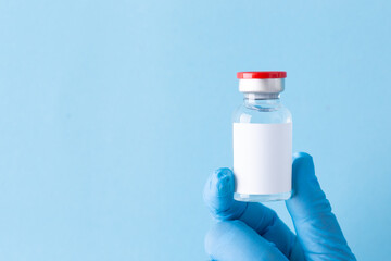 Medicine bottle for injection, Medical glass vial for vaccination. Science equipment, liquid drug or vaccine from treatment, flu in laboratory, hospital or pharmacy, copy space blue background.