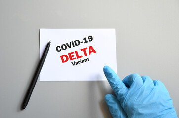 doctor hand with blue glove with white card and text Covid-19 Delta Variant and pen. Medical and...
