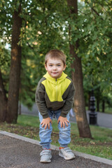 Fototapeta premium portrait of a small child, a boy of 3 years old, against the background of a park. beautiful caucasian blonde child on the background of trees