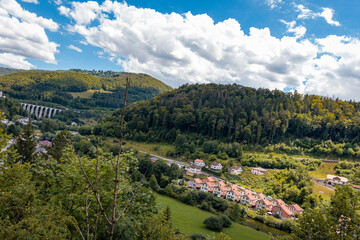mountains with many trees surrounded by houses and a monastery and train line