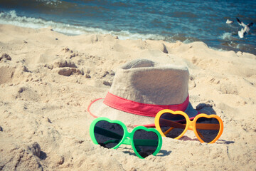 Fototapeta na wymiar Sunglasses and straw hat on sand at beach. Travel and vacation time