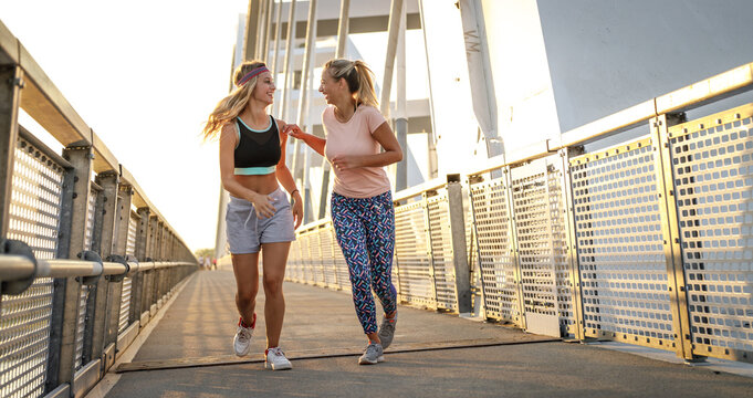 Two best friends jogging over the city bridge.Joying in summer day.	
