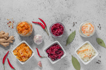 Homemade fermented food: kimchi cabbage and sauerkraut sour in glass jars and salad bowls with ingredients on the grey background. Concept healthy probiotics vegetarian food. Asian cuisine.