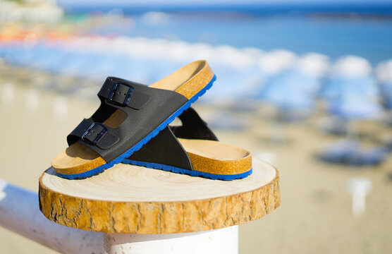 Blue with black men's sandals on a wooden log in summer time