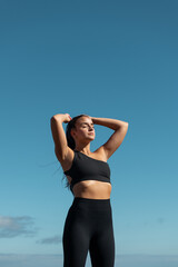 photograph of a girl in black sportswear practicing yoga and sports outdoors with beautiful views behind her