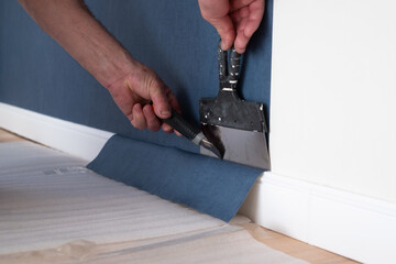 Man cutting wallpaper. Maintenance repair works renovation in the flat.