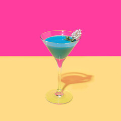 A vibrant blue cocktail with a white flower with bright magenta background and warm yellow bottom. Party optimistic concept.