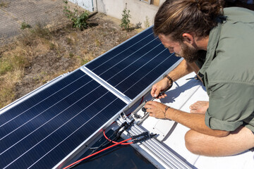 Man connecting solar panels on top of a camper van