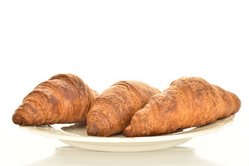 Three fragrant croissants with chocolate filling on a white ceramic plate, close-up, isolated on white.