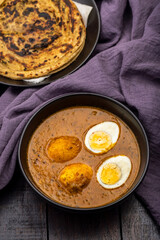 Fried egg curry or Anda Masala served in a bowl with  lachha parantha