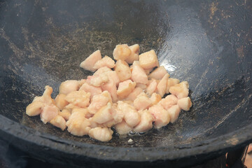 Pieces of raw lamb fat dumba are fried in a black cauldron, cooking food