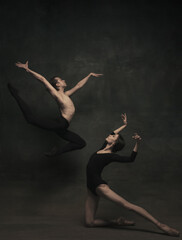 Beautiful graceful woman and man, ballet dancers in art performance dancing isolated over dark...