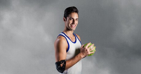Portrait of caucasian male handball player holding a ball smiling against grey background