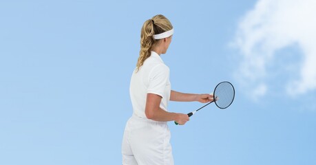 Rear view of female badminton player playing against clouds in blue sky