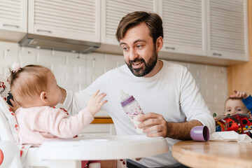 White father feeding his daughter while babysitting at home