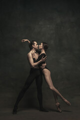 Beautiful graceful woman and man, ballet dancers in art performance dancing isolated over dark...