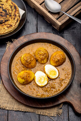 Fried egg curry or Anda Masala served in a bowl with  lachha parantha