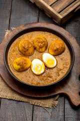 Fried egg curry or anda masala served in a white bowl and copy space