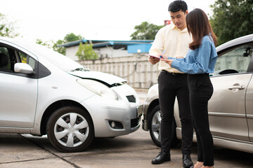 Fototapeta na wymiar Asian women driver Talk to Insurance Agent for examining damaged car and customer checking on report claim form after an accident. Concept of insurance and car traffic accidents.