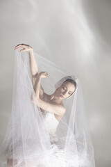 Young graceful balerina in image of white swan in art performance isolated on gray white background. © Lustre Art Group 
