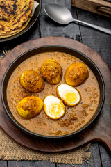 Fried egg curry or Anda Masala served in a bowl with  lachha parantha