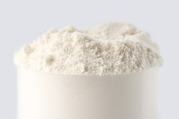 Heap of protein powder on white background. Scoops Of Protein Powder. Measuring spoon and heap of vanilla protein powder.