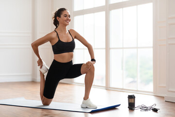 Young woman stretching leg exercising on yoga mat