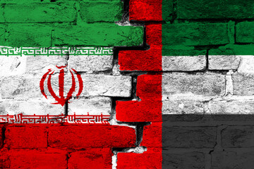 Concept of the relationship between Iran and the United Arab Emirates with two painted flags on a damaged brick wall