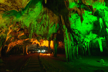 natural gray stalagmite or stalactite with green and red led light in dark cave in mountain