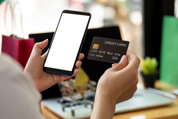 woman holding smart phone and credit card for shopping online.Blank screen monitor for graphic display montage.