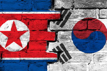 Concept of the relationship between North Korea and South Korea with two painted flags on a damaged brick wall