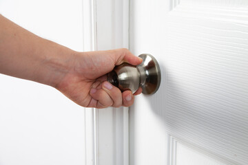 left hand holding door knob, opening door in the house
