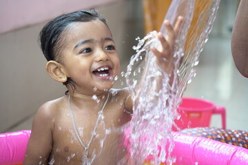 indian baby boy enjoying bath in an inflatable pool