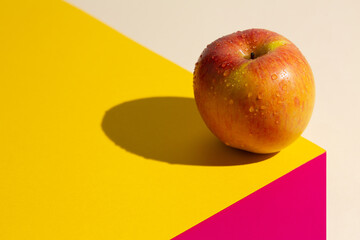 Fuji apple on a yellow and pink cube