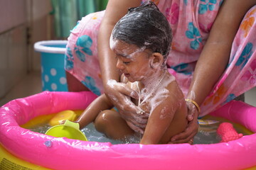 indian baby boy enjoying bath in an inflatable pool