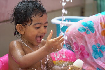 indian baby boy enjoying bath in an inflatable pool