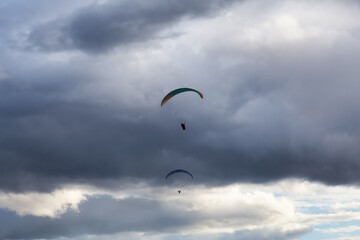 Adventurous People Flying on a Paraglider around the mountains. Savona, British Columbia, Canada.