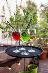 Cocktail tray. The waiter is holding a tray of cocktails. Four glasses with drinks on the background of the summer terrace. Summer drinks in glasses