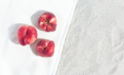 Peaches lie on a towel on the beach. Summer concept